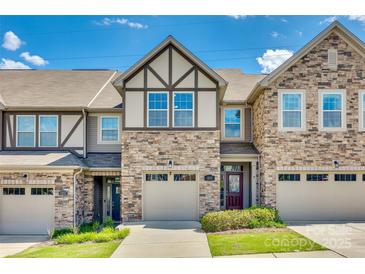 Charming townhome featuring a stone and siding exterior with attached garage under a clear blue sky at 1213 Bhaltair Ln, Fort Mill, SC 29708