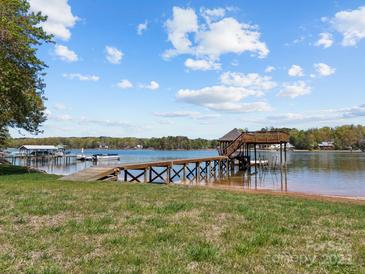 Inviting lakefront property features a wooden dock with a covered sitting area and ample space for boat mooring at 126 Balmoral Dr, Mooresville, NC 28117