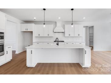 Bright kitchen features a large center island, modern fixtures, white cabinetry, and wood flooring at 3057 Tramore Dr, Harrisburg, NC 28075