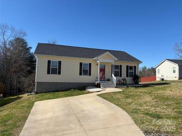 Charming single-story home featuring a well-manicured lawn and a concrete driveway on a sunny day at 52 Restful Ln, Hickory, NC 28601