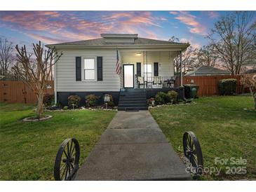 Charming home with inviting porch, black shutters, and well-manicured lawn at dusk at 1411 Congress St, Gastonia, NC 28054