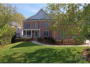 Charming two-story red brick home with a well-manicured lawn and a welcoming front porch at 15009 Lisha Ln, Charlotte, NC 28277