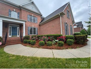Charming brick home featuring a landscaped front yard with colorful flower beds and a covered front porch at 15009 Lisha Ln, Charlotte, NC 28277
