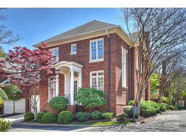 Charming two-story brick home with a manicured lawn, lush landscaping, and inviting front entrance with white columns at 2021 Nolen Park Ln, Charlotte, NC 28209