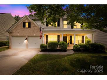 Charming two-story home featuring a brick and siding exterior, a two-car garage, and a welcoming covered front porch at 20827 Brinkley St, Cornelius, NC 28031
