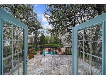 Inviting back porch with stone tiles looks out to the lush backyard and swimming pool at 2132 Rolston Dr, Charlotte, NC 28207
