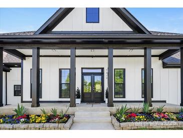 Inviting front porch with black accents, decorative columns, and colorful flowerbeds enhances curb appeal at 7419 Tesh Rd, Monroe, NC 28110