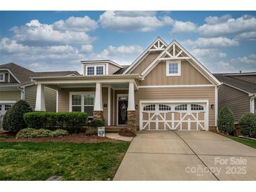 Charming home featuring a two-car garage, covered porch with stone accents, and manicured lawn at 1022 Bimelech Dr, Indian Trail, NC 28079