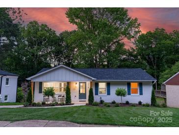 Charming single-story home with well-manicured lawn and inviting front porch at dusk at 215 Wyanoke Ave, Charlotte, NC 28205