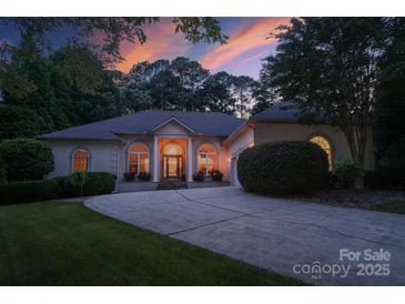 Elegant home exterior featuring a circular driveway, arched windows, and inviting front entrance at dusk at 2587 Penngate Dr, Sherrills Ford, NC 28673