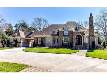 Stately brick home features a manicured lawn, circular drive, and elegant architectural details at 7295 Three Sisters Ln, Concord, NC 28027
