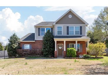 Charming two-story home featuring brick and siding, a welcoming front porch, and manicured landscaping at 4519 S Potter Rd, Monroe, NC 28112