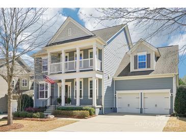 Charming two-story home with a double-door garage, columns, and a welcoming front porch with American Flag at 1034 Currituck Way, York, SC 29745