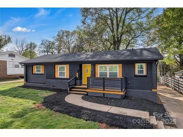 Charming single-story home featuring a black painted brick exterior, yellow door, and fresh landscaping at 1814 Eastway Dr, Charlotte, NC 28205