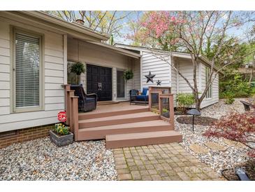 Charming home exterior features a wooden porch, double front doors, and a stone walkway, framed by flowering trees at 27 Heritage Ct, Lake Wylie, SC 29710