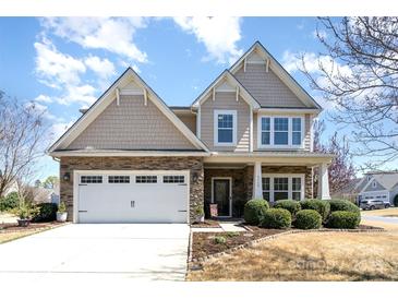 Charming two-story home featuring stone accents, attached garage and a beautifully landscaped front yard on a sunny day at 5115 Sand Trap Ct, Monroe, NC 28112