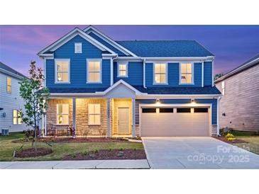 Charming two-story blue home featuring a two-car garage, stone accents, and a well-manicured lawn at 6020 Chumbley Point Rd # 73, Charlotte, NC 28215