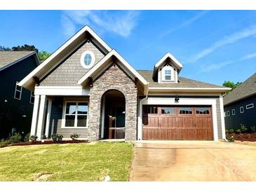 Charming single-Gathering home with a stone entryway, green lawn, and attached two-car garage at 178 Fulworth Nw Dr # 64, Concord, NC 28027