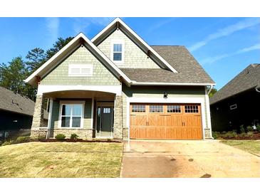Charming craftsman-style home with a beautiful wood garage door and stone-accented porch at 182 Fulworth Nw Dr # 63, Concord, NC 28027