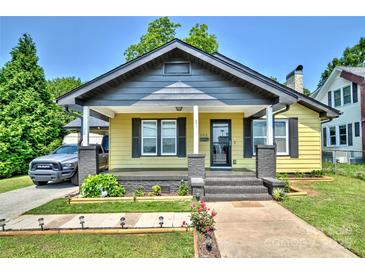 Charming yellow home featuring a welcoming front porch, gray accents, and well-maintained landscaping at 302 Griffith Rd, Monroe, NC 28112