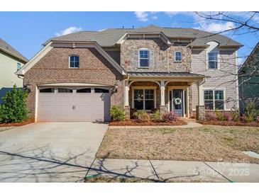 Charming brick and stone two-story home with a two-car garage and manicured front lawn at 11144 Limehurst Pl, Charlotte, NC 28278