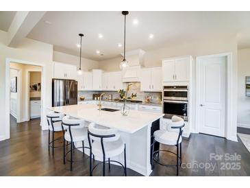 Bright kitchen with white cabinetry, large island with seating, and stainless steel appliances at 11144 Limehurst Pl, Charlotte, NC 28278
