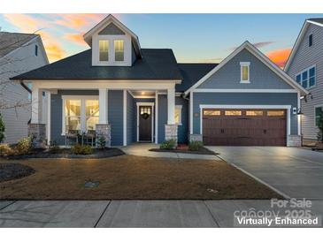 Charming home featuring a two-car garage, covered porch, and manicured front lawn at 1447 Encore Ln, Waxhaw, NC 28173