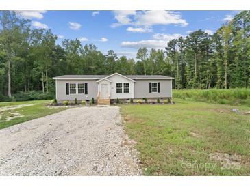 Charming single-story home with gray siding, black shutters, and a gravel driveway surrounded by lush greenery at 253 Artemis Pl # 27, Kershaw, SC 29067
