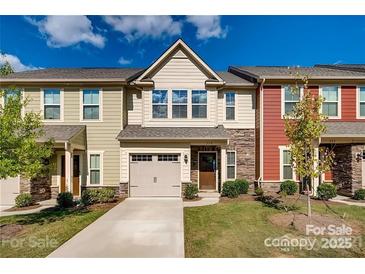 Charming townhome with attached garage, stone accents and landscaped yard on a beautiful partially cloudy day at 319 Pond Place Ln, Matthews, NC 28104
