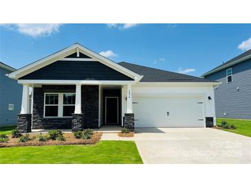 Charming single-Gathering home with stone accents, white siding, manicured lawn, and two-car garage on a sunny day at 1234 Morehead Dr, Salisbury, NC 28144
