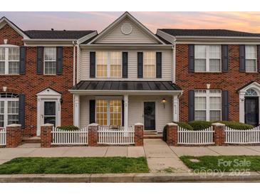 Charming two-story townhome featuring a classic brick facade, black shutters and a welcoming front porch at 1720 Chamberside Dr, Rock Hill, SC 29730