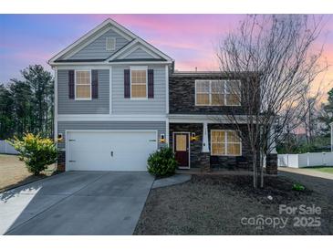 Charming two-story home featuring a stone facade, gray siding, and a well-maintained front yard at 428 Wheat Field Dr, Mount Holly, NC 28120