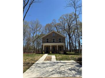 Charming two-story home with stone accents, a welcoming porch, and a freshly poured concrete driveway at 4731 Whispering Oaks Dr, Charlotte, NC 28213