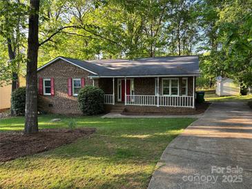 Charming brick home featuring a well-maintained lawn and red shutters at 10607 Wood Meadow Dr, Charlotte, NC 28227