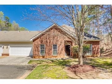 A well-kept brick townhome featuring a manicured lawn, a tree, and a welcoming entrance at 2023 Aragon Ln, Gastonia, NC 28056