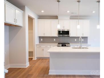 Bright kitchen features white cabinets, stainless steel appliances, and an island with quartz countertops at 219 Halemarg Dr, Belmont, NC 28012