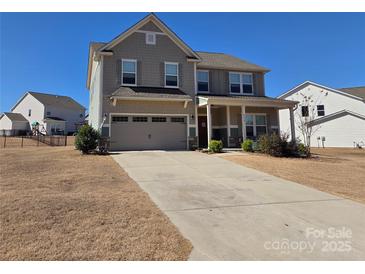Two-story home featuring a two-car garage, covered front porch, and well-maintained landscaping against a clear blue sky at 4630 Bent Green Ln, Monroe, NC 28112