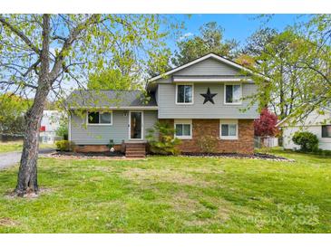 Charming two-story home with a combination of brick and siding, complemented by a well-maintained lawn and mature trees at 1308 Gaston Way, Dallas, NC 28034