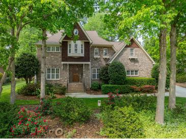 Traditional brick home featuring mature landscaping, a bay window, and a welcoming front entrance at 4599 Rustling Woods Dr, Denver, NC 28037