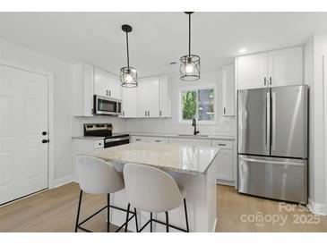 Modern kitchen features white cabinets, stainless steel appliances, granite countertops, and a central island at 530 S Trenton St, Gastonia, NC 28052