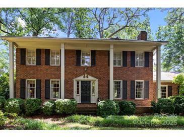 Charming red brick home featuring stately white columns and dark shutters surrounded by lush landscaping at 5510 Sardis Rd, Charlotte, NC 28270