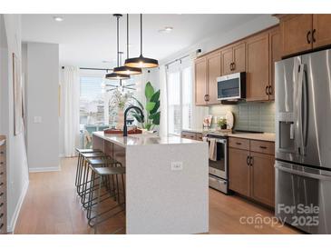 Bright kitchen features a large island with seating, stainless steel appliances, and modern light fixtures at 5604 Kingspan Dr, Charlotte, NC 28217