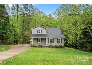 Charming two-story home featuring gray siding, black shutters, and a well-manicured lawn surrounded by lush trees at 2717 Stockwood Dr, Gastonia, NC 28056