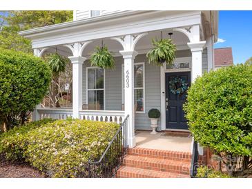 Charming front porch featuring brick steps, white columns, hanging ferns, and a dark-colored front door with a wreath at 6603 Park Meadows Pl, Huntersville, NC 28078