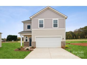 Two-story home featuring neutral siding, brick accents, attached two-car garage, and a well-manicured lawn at 714 Olde England Dr, Lincolnton, NC 28092