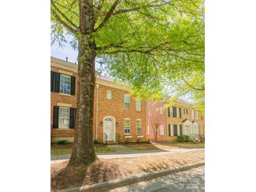 Charming brick townhome with black shutters and a welcoming front porch, shaded by a mature tree at 165 Singleton Rd, Mooresville, NC 28117