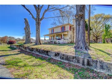 Two story home with a charming porch, mature trees, and red shutters at 2114 Whitworth Rd, Cherryville, NC 28021