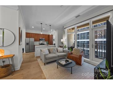 Bright living room featuring an open floor plan, hardwood floors, and a balcony with city views at 230 S Tryon St # 610, Charlotte, NC 28202