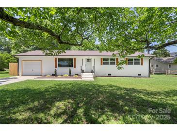Charming home with green lawn, brick facade, matching shutters, and a lovely shade tree in a desirable neighborhood at 1315 Vickie Ln, Matthews, NC 28104