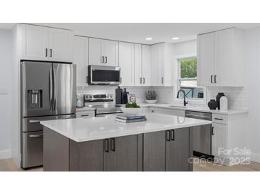 Modern kitchen featuring white cabinets, stainless steel appliances, and a large island with a white countertop at 1315 Vickie Ln, Matthews, NC 28104